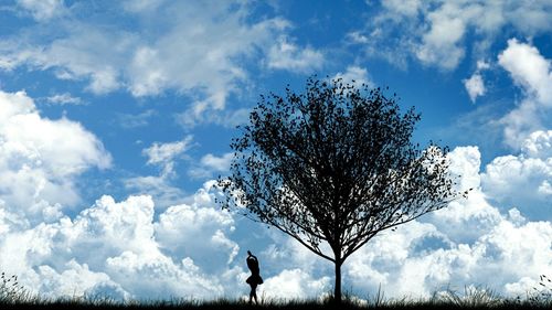 Low angle view of trees against cloudy sky