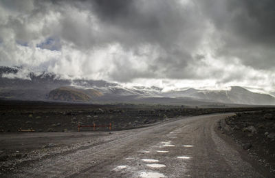 Road by mountains against sky
