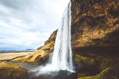 Low angle view of waterfall falling from mountain