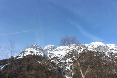 Low angle view of snowcapped mountains against blue sky