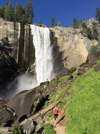 Rear view of woman walking towards waterfall