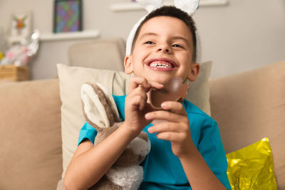 Portrait of smiling young woman sitting on sofa at home