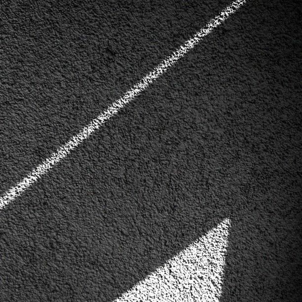 road marking, street, road, the way forward, shadow, asphalt, textured, pattern, high angle view, transportation, sunlight, wall - building feature, outdoors, no people, sidewalk, day, diminishing perspective, built structure, architecture, vanishing point