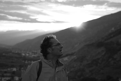 Man looking away while standing against mountain