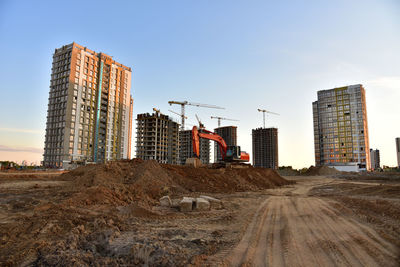 Excavator on earthmoving at construction site. road work and dig pit foundation. tower cranes 