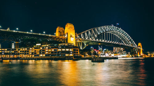 Illuminated bridge over river at night