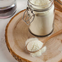 Collagen in the form of a white powder in a glass jar and on a wooden spoon. skin care