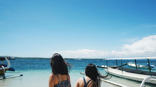 Women standing on shore against sky