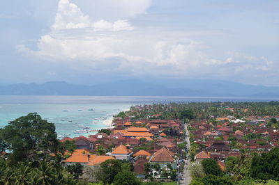 Aerial view of townscape by sea against sky