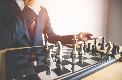 Midsection of businessman playing chess in office