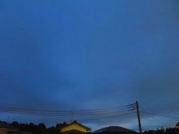 Low angle view of electricity pylon against blue sky