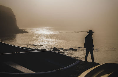 Silhouette of adult man with fishing boats on beach during sunrise. almeria, spain