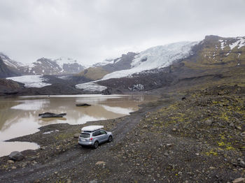 Car driving on gravel road near montain glacier