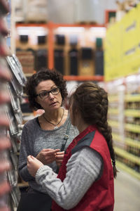 Side view of saleswoman talking to female customer in hardware store