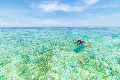 Man swimming in sea against sky