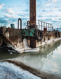 Metal structure by river against sky