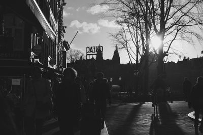 People walking on city street at sunset