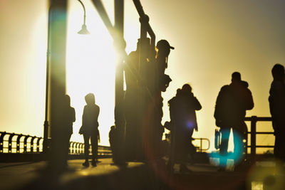 Silhouette people standing against sky during sunset