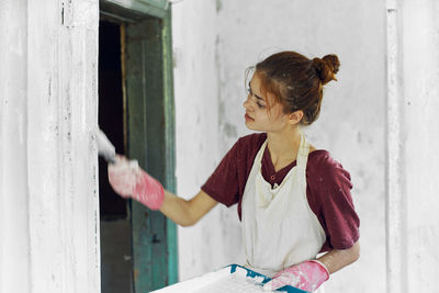 Side view of woman looking through window