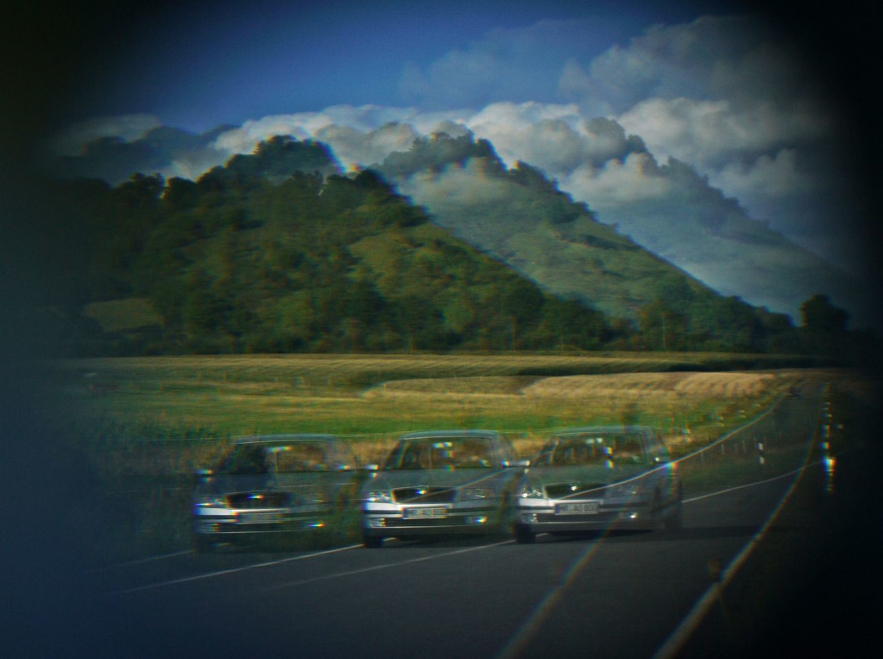 CAR ON ROAD AMIDST FIELD AGAINST SKY