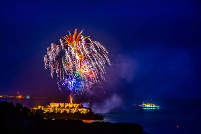 Firework display over sea against sky at night