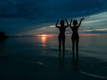 Silhouette people at beach against sky during sunset