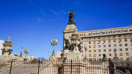 Low angle view of statue of building against blue sky