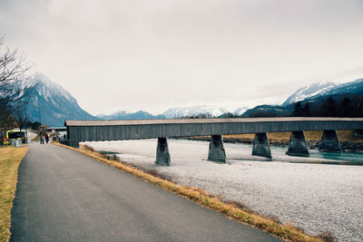 Road by lake against sky during winter