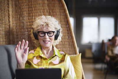 Senior woman with headphones having video call on tablet