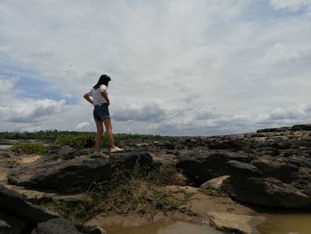 Full length of man standing on rock against sky