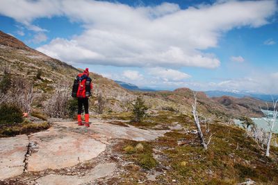 Rear view of man standing on mountain against sky