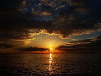 Scenic view of sea against dramatic sky during sunset