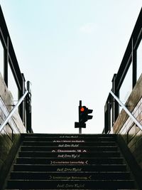 Low angle view of staircase leading towards red light against sky