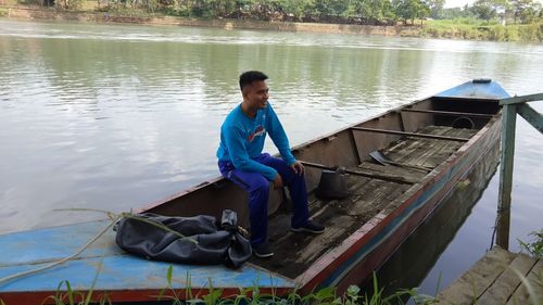 Young man sitting on boat in lake