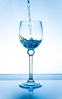 Close-up of water drop on glass against white background