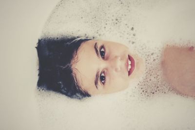 Portrait of boy taking bath in tub at bathroom