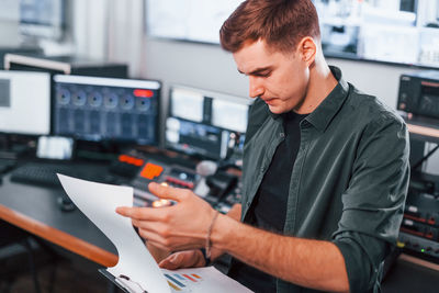 Document with scenario. young man is indoors in the radio studio is busy by broadcast.