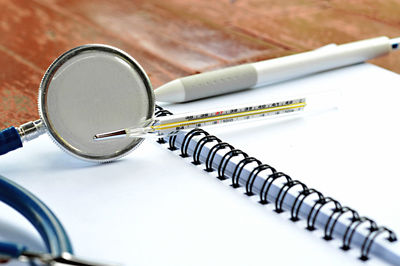 High angle view of medical equipment with spiral notebook and pen on table