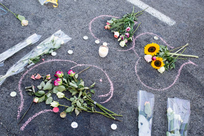 High angle view of bouquets and tea lights on chalk drawing at road after terrorist attack