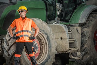 Manual worker standing against construction vehicle