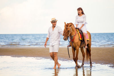 Couple with horse on shore at beach