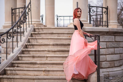 Woman with umbrella standing on staircase