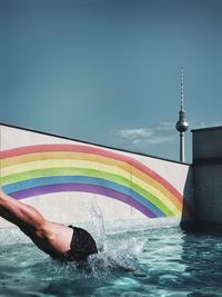 Low section of man jumping into pool against sky