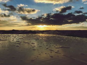 Close-up of wet beach against sky during sunset