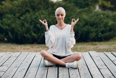 Portrait of young woman sitting on boardwalk