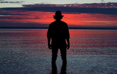 Silhouette of man in shallow water at sunset