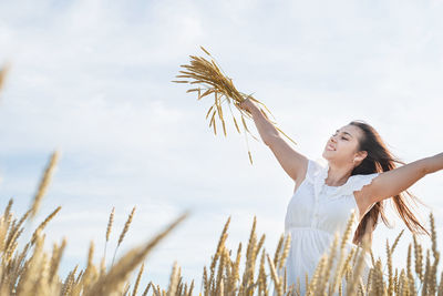 Side view of young woman standing against sky