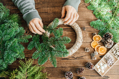 Top view of male hands making a christmas wreath from natural spruce branches 
