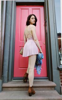 Rear view portrait of beautiful woman standing against red door