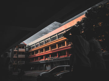 Rear view of silhouette man standing by window in city